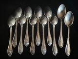 six cuillères en argent sont alignées sur une surface noire