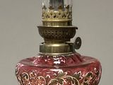 une lampe en verre rouge et doré posée sur une table en bois
