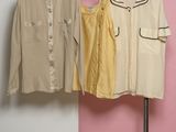 three shirts hanging on a rack in front of a pink and white wall