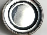 a silver plate with a handle on a white surface