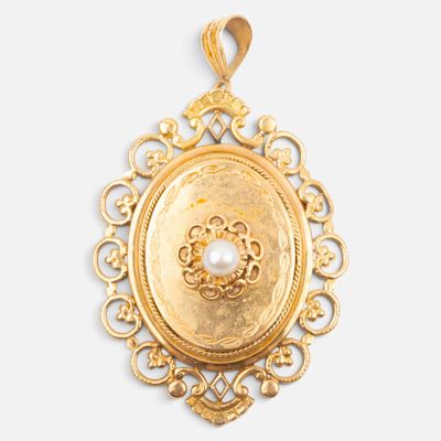 a close up of a gold pendant with a pearl in the center
