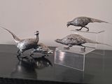 three metal birds that are standing on a table