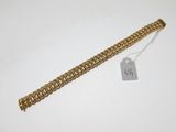 a close up of a gold chain bracelet with a tag on it