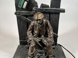 bronze statue of a man sitting on a bench with a computer