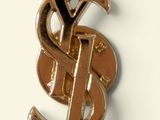 a gold ysl pin with a dollar sign on it