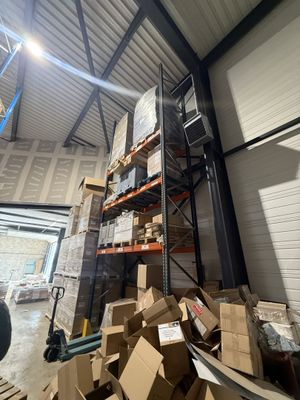 une grande pile de cartons dans un entrepôt, avec un chariot élévateur