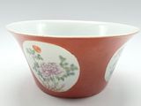 un bol rouge orné de fleurs, posé sur un fond blanc