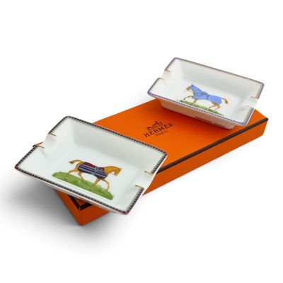 two porcelain dishes with horses painted on them sitting on an orange box