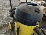 un aspirateur jaune et noir posé par terre à côté d'un tas de bois