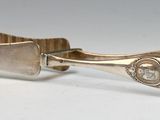 a silver cuff with a diamond in it on a white surface