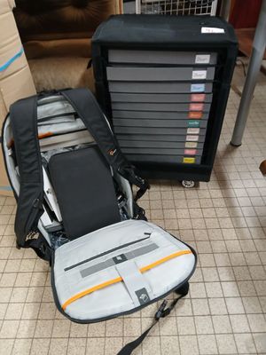 a suitcase and a backpack on the floor next to a stack of boxes