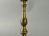 a brass table lamp with a white candle on top of it