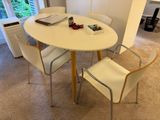 une table blanche avec quatre chaises et un ordinateur portable posé dessus