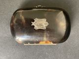 an antique silver cigarette case with a lion emblem on the front