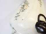un vase blanc muni d'une anse noire posé sur une table