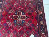 someone is standing in front of a red rug with a cross on it
