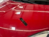 a close up of a red car with a sticker on it ' s hood