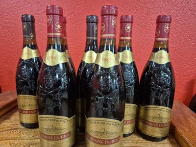 six bottles of wine are lined up on a wooden table