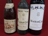 three bottles of wine are lined up on a red surface