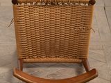 a wooden rocking chair with a woven seat on a tile floor