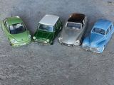 Quatre voitures miniatures sont alignées en rang dans un parking