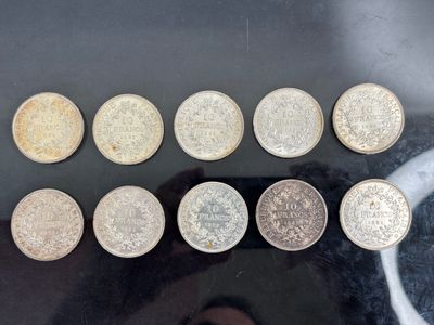 six pièces de monnaie britanniques différentes posées sur une table, à côté de la main d'une personne