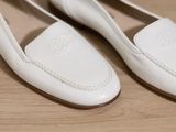 pair of white loafers on a wooden surface with a brown sole