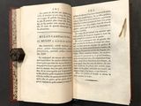 an open book with a wax stamp on it sitting on a table