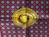 a red and white tie with a gold medallion on it