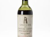 a bottle of red wine sitting on top of a white table