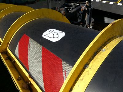 un gros tuyau sur lequel est inscrit un numéro, posé au milieu d'un champ