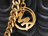 a close up of a black quilted bag with a gold chain