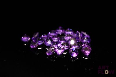 Des cristaux d'améthyste violets sont dispersés sur une surface noire