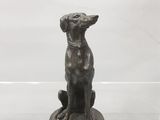 une statue en bronze représentant un chien assis sur une table
