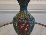 a vase sitting on a table with a white wall in the background