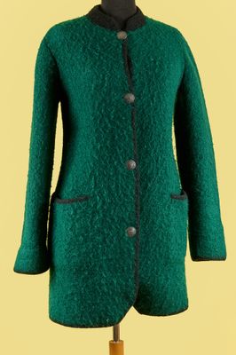 un manteau vert sur un mannequin, posé sur un fond jaune