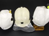 three white hard hats sitting on top of each other on a black surface