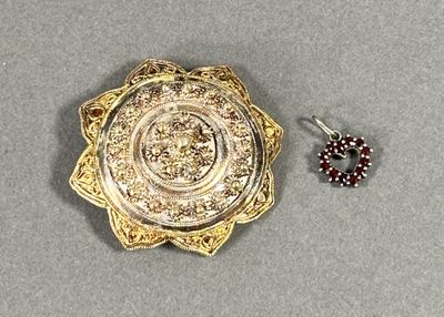 une broche en or et une paire de boucles d'oreilles posées sur une table