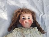 a doll that is laying down on a white sheet