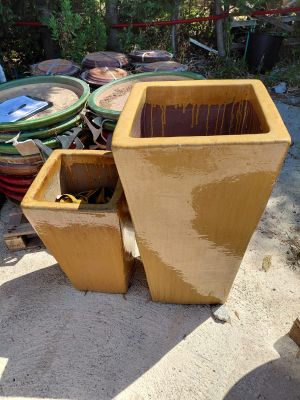 a large yellow planter sitting on the ground next to a pile of trash