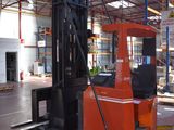a fork lift truck in a warehouse with a man in the background