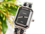 a close up of a wrist watch with a flower in the background