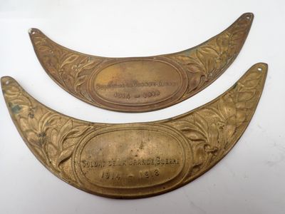 two antique brass plaques with engraved names on them on a white surface