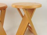 pair of wooden stools with crossed legs on a white background