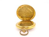 a close up of a gold pocket watch on a white surface