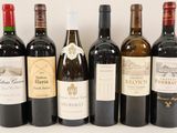 six bottles of wine are lined up in a row on a white surface