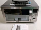 a silver microwave with a frying pan on top of it