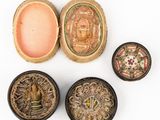 four small boxes with decorative designs on them sitting on a white surface