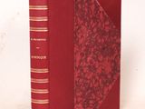 un vieux livre à la couverture rouge posé sur une surface blanche