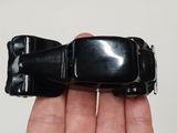 a person holding a small black toy car in their hand